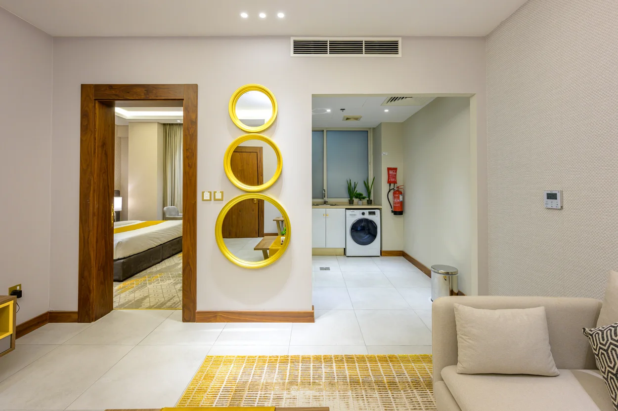 Abraj INN Suites, Doha Hotels: suite hallway between the bedroom door and an open kitchen with sink, cabinets and a washer