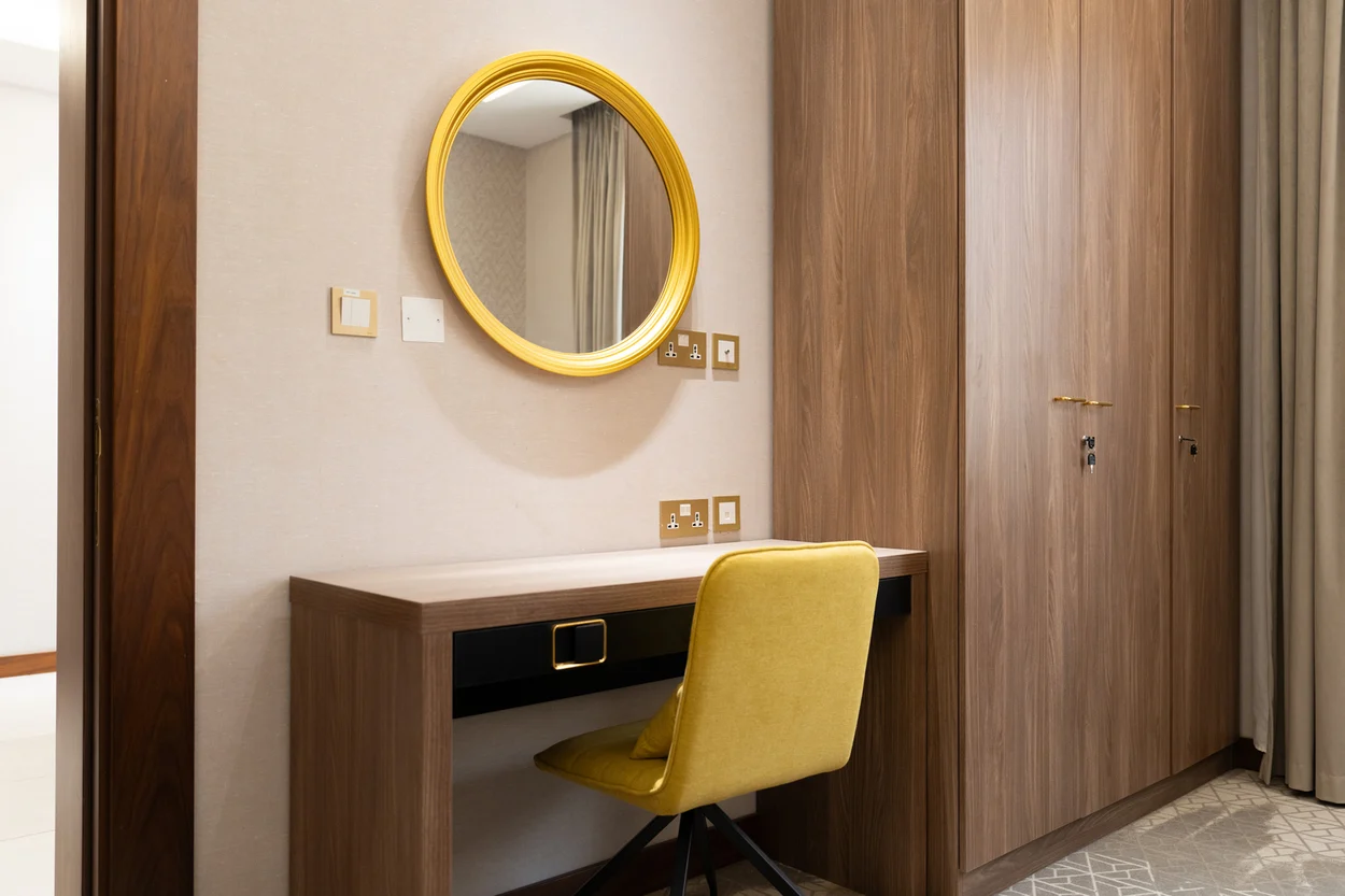 Abraj INN Suites, Doha Hotels: built-in walnut desk, mustard swivel chair, round gold mirror and full-height wardrobe