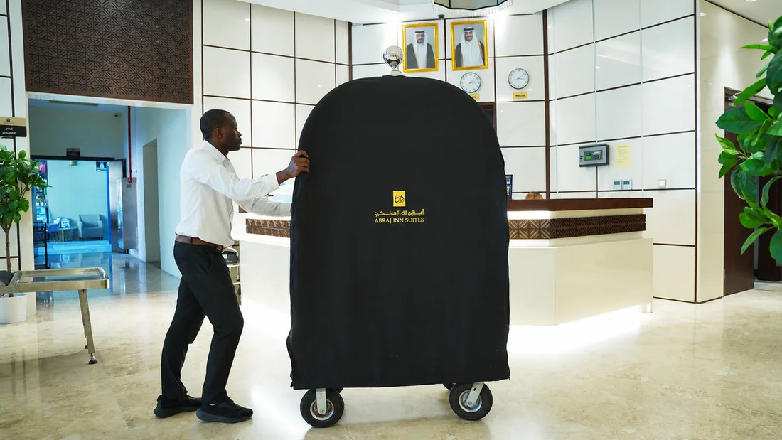 Abraj INN Suites, Doha Hotels: a porter pushing a luggage trolley past the white reception desk in the lobby