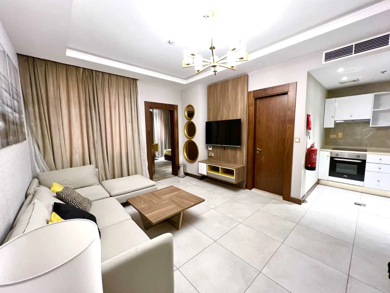 Abraj INN Suites, Doha Hotels: open-plan suite with a cream corner sofa, wall TV and a kitchenette with oven and hob