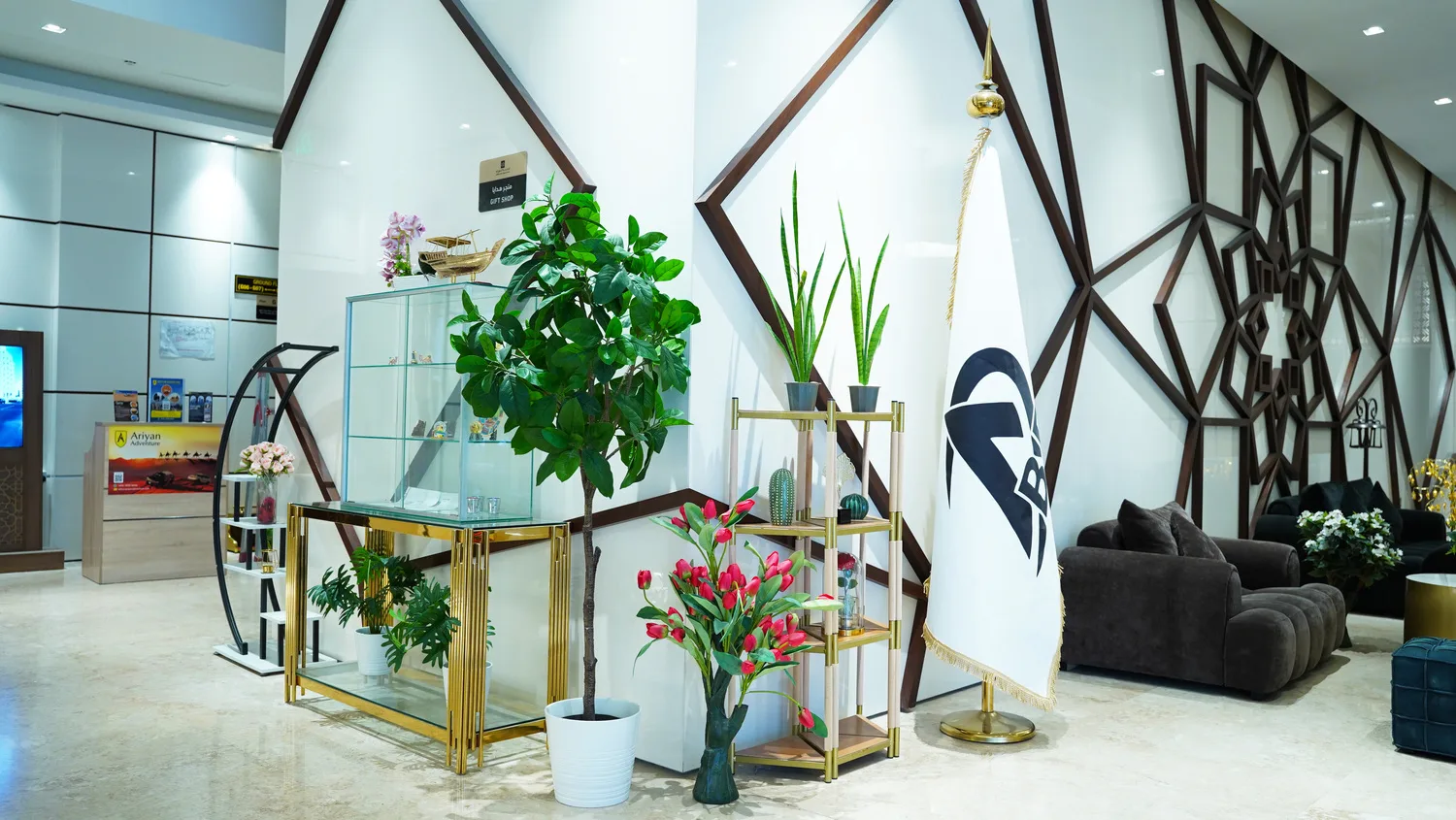 Abraj INN Suites, Doha Hotels: lobby corner with a glass display cabinet, gold console, faux ficus and a grey sofa