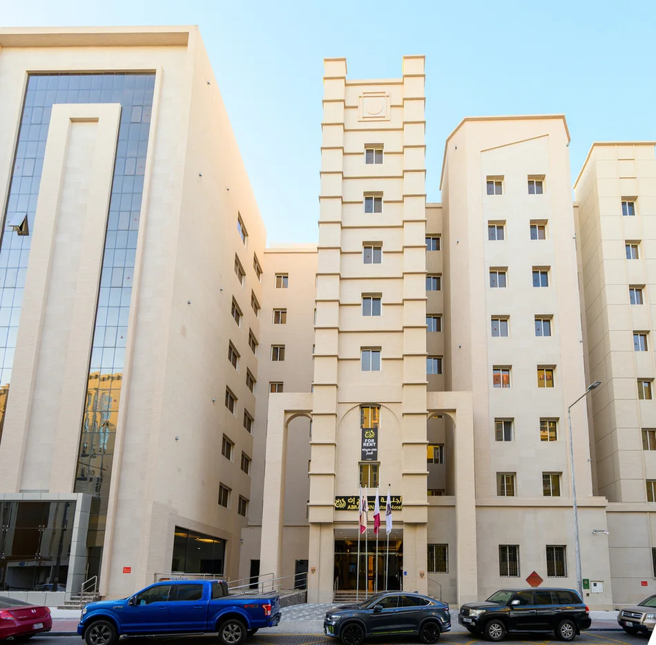Abraj INN Suites, Doha Hotels: beige stone facade of about eight storeys, arched main entrance and Qatari flags