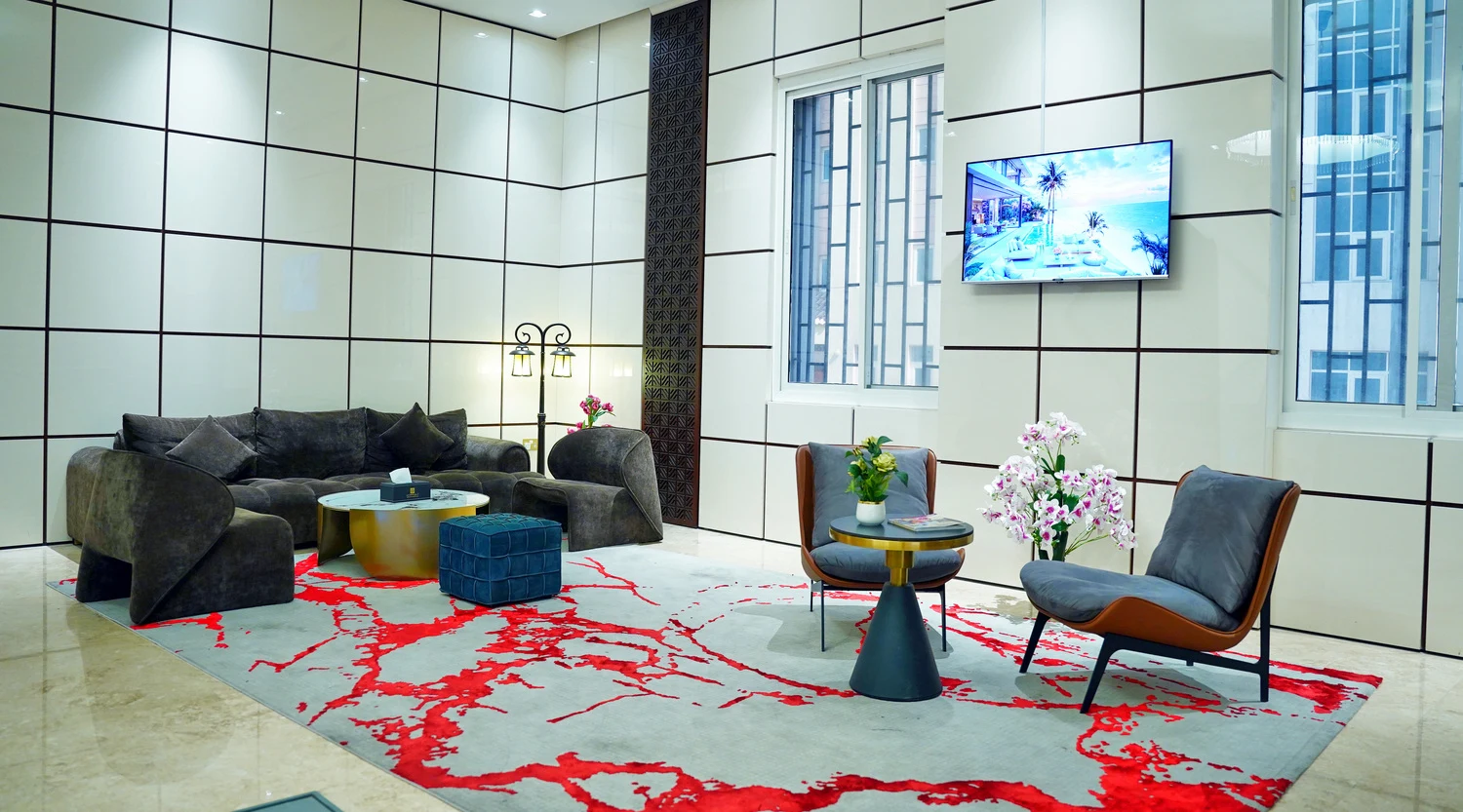 Abraj INN Suites, Doha Hotels: double-height lobby lounge with grey velvet seating, a gold drum table and tall windows.