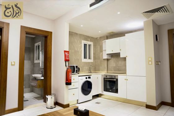 Suite kitchen with washing machine and en-suite bathroom door at Abraj Suites Hotel Doha
