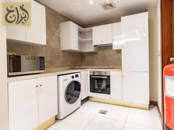 Fully equipped kitchen with oven, microwave and washing machine in a one-bedroom suite at Abraj Suites Hotel Doha