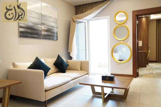 Separate living room with balcony access in a one-bedroom apartment at Abraj Suites Hotel Al Mansoura