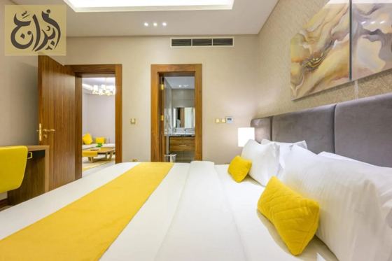 Suite bedroom with king bed and dressing mirror at Abraj Suites Hotel, Al Mansoura, Doha