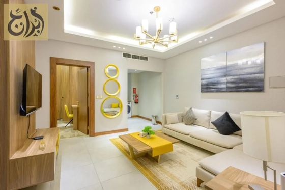 Living room with smart television and seating in a one-bedroom suite at Abraj Suites Hotel Doha